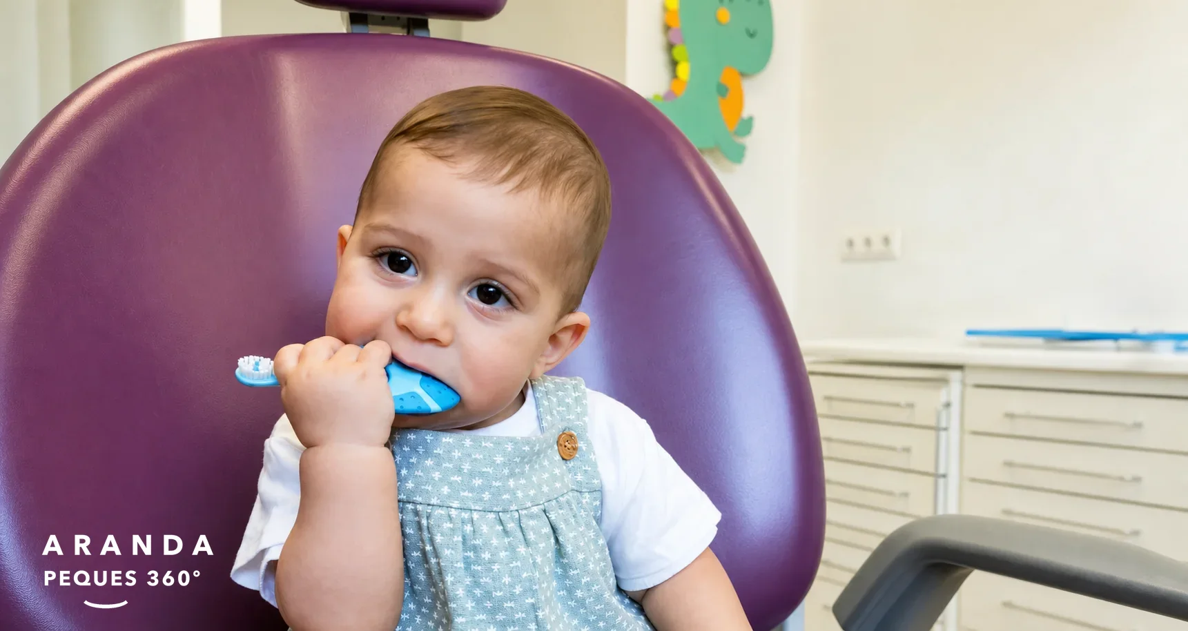 Bebé en sillón dental mordiendo un cepillo infantil azul