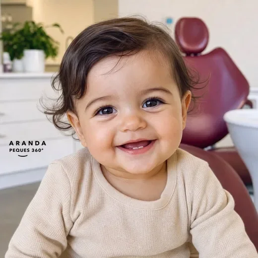 Bebé sonriendo con sus primeros dientes en el sillón dental de Clínica Dental Aranda