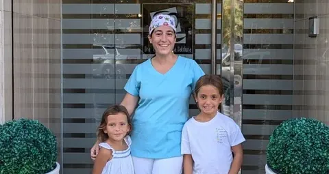 Dra. Isabel Aranda con dos niñas en la entrada de la clínica dental